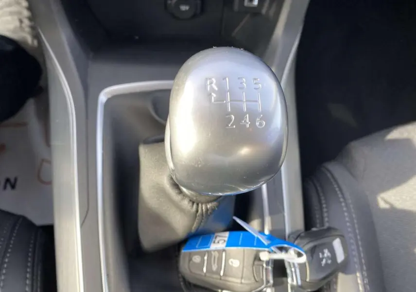 Le levier de vitesses manuel argenté de la Peugeot 308 blanche, vu en gros plan depuis l'intérieur.