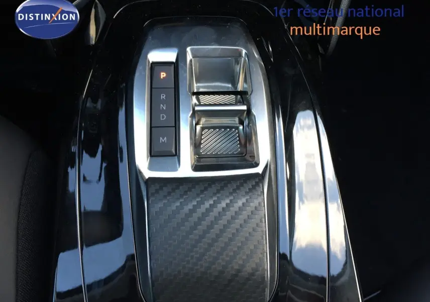 Gros plan sur la console centrale avec levier de vitesses automatique et finition carbone du Peugeot 208 gris selenium 2025.