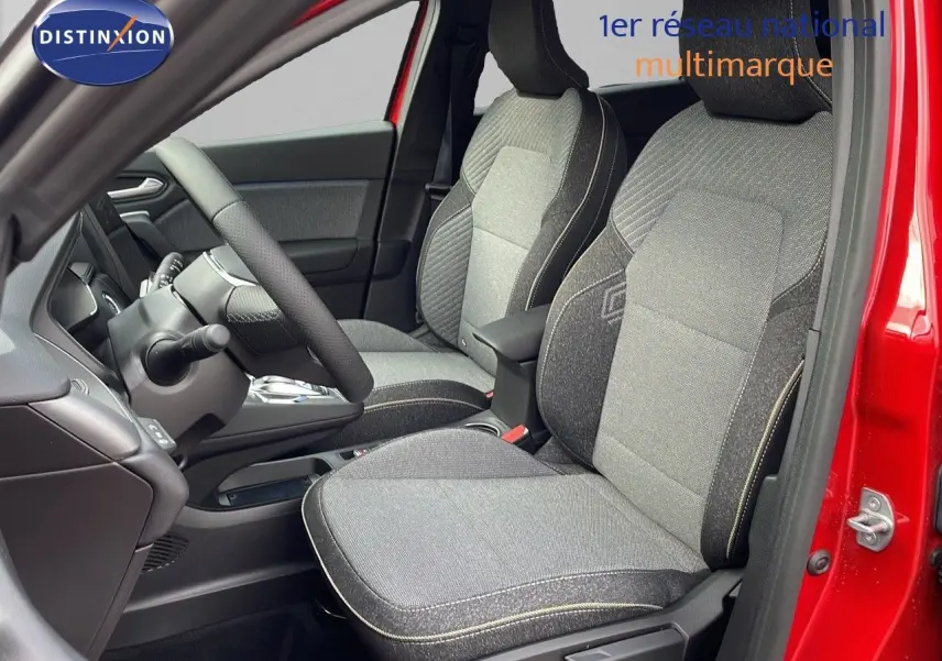 Vue intérieure côté conducteur du Renault Captur E-Tech rouge passion, montrant les sièges tissu gris et noir avec coutures contrastées.