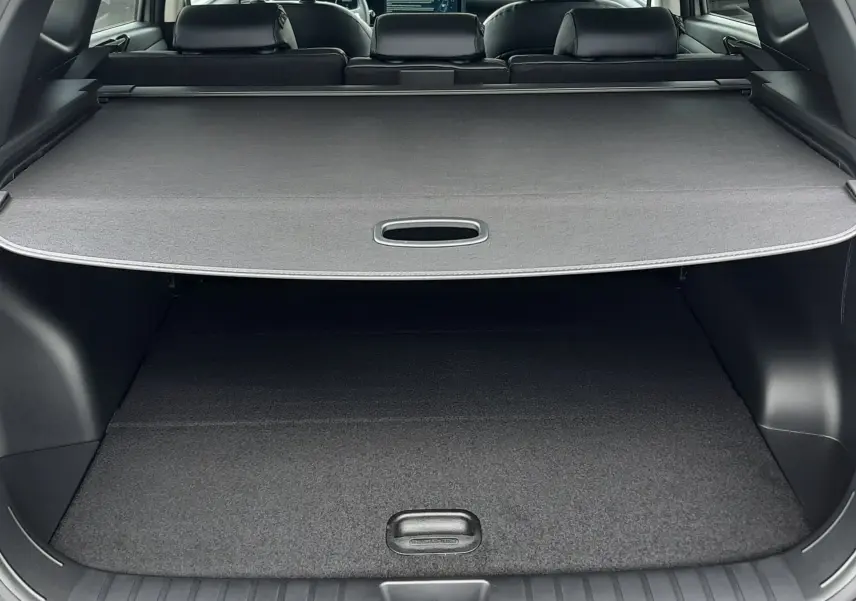 Vue arrière du coffre du Hyundai Tucson gris Shimmering Silver 2025, avec cache-bagages déployé et intérieur noir visible.