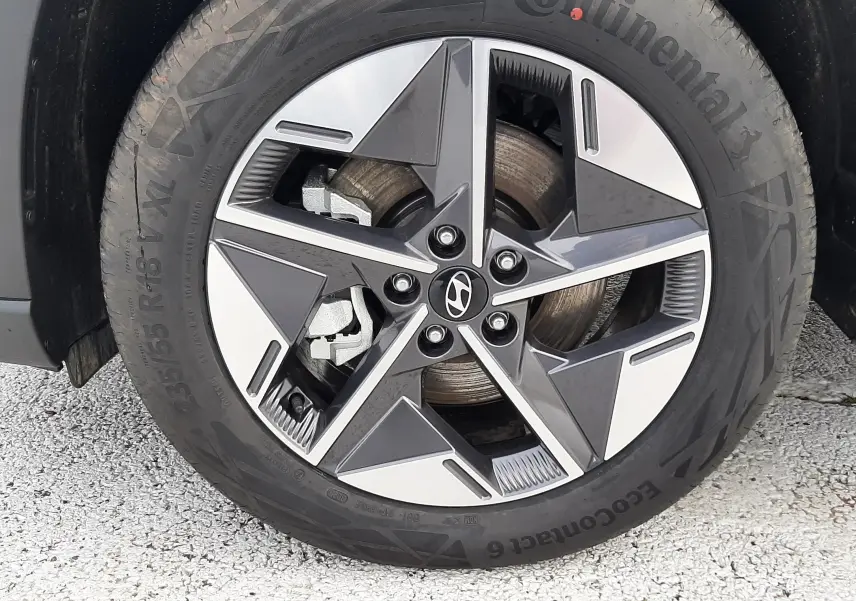 Gros plan sur la roue avant droite du Hyundai Tucson 2025 gris, avec jante alliage bicolore et logo Hyundai central.