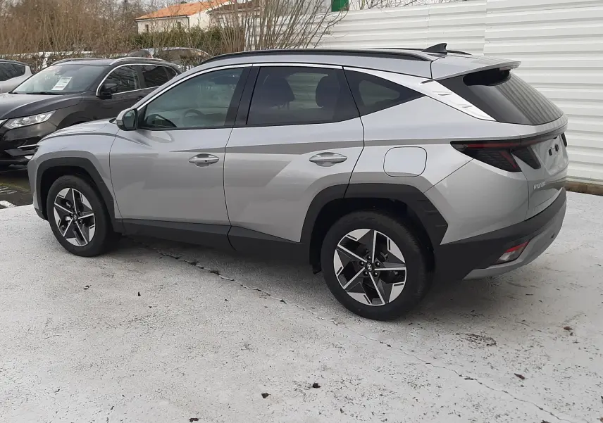Vue côté droit arrière du Hyundai Tucson 2025 gris Shimmering Silver avec jantes bi-ton et feux arrière LED distinctifs.