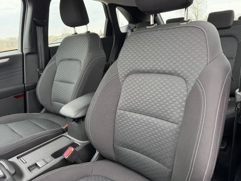 Vue intérieure rapprochée des sièges avant gris foncé du Ford Kuga 1.5 EcoBoost 150ch Titanium 2024, avec surpiqûres apparentes.