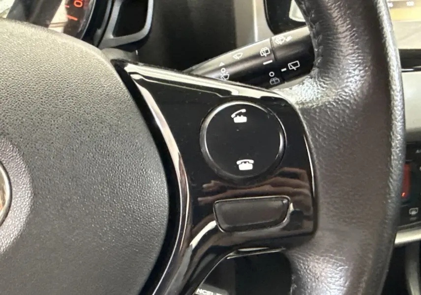 Gros plan sur le volant noir de la Toyota Aygo 2017, montrant les commandes d’appel téléphonique intégrées.