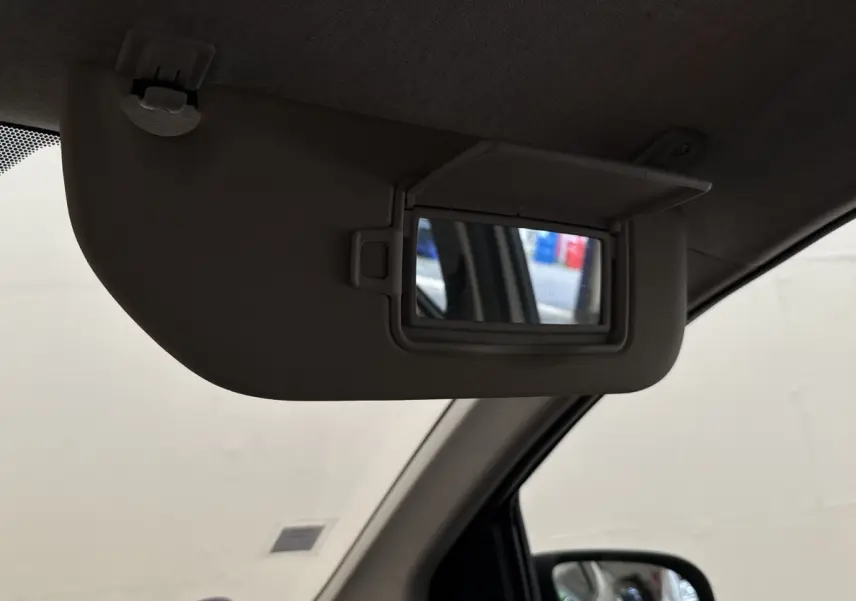 Détail du pare-soleil côté conducteur avec miroir de courtoisie ouvert dans une Toyota Aygo gris clair.