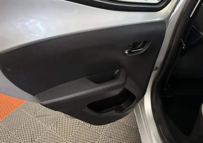 Vue rapprochée de la porte arrière gauche grise claire d’une Toyota Aygo 2017 avec panneau intérieur noir et poignée intégrée.