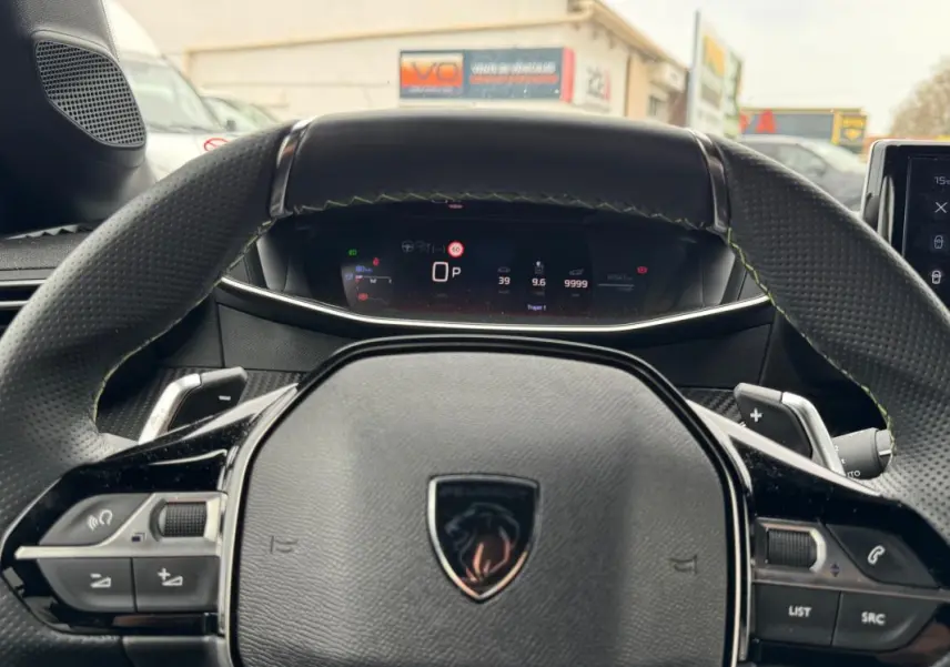 Vue rapprochée du volant multifonction noir et du tableau de bord numérique d'une Peugeot 208 Hybrid 110 gris 2025.