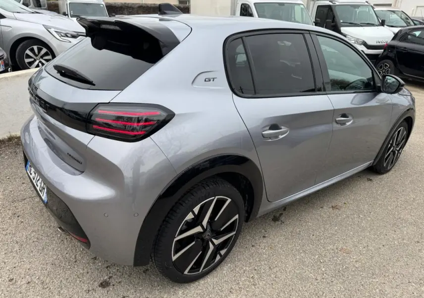 Peugeot 208 Hybrid gris vue 3/4 arrière droit, jantes alliage 17 pouces et logo GT sur l'aile arrière.