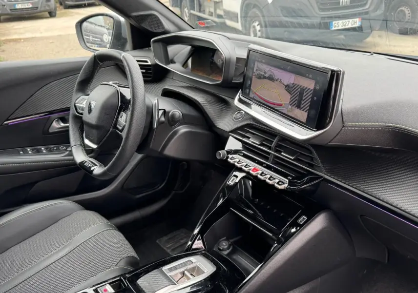 Vue intérieure côté conducteur du Peugeot 208 Hybrid 110 e-DCS6 GT 2025, avec tableau de bord moderne et écran tactile affichant la caméra de recul.