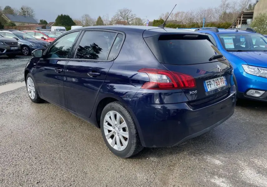 Peugeot 308 bleu foncé vue 3/4 arrière droit, avec feux arrière distinctifs et vitres teintées.