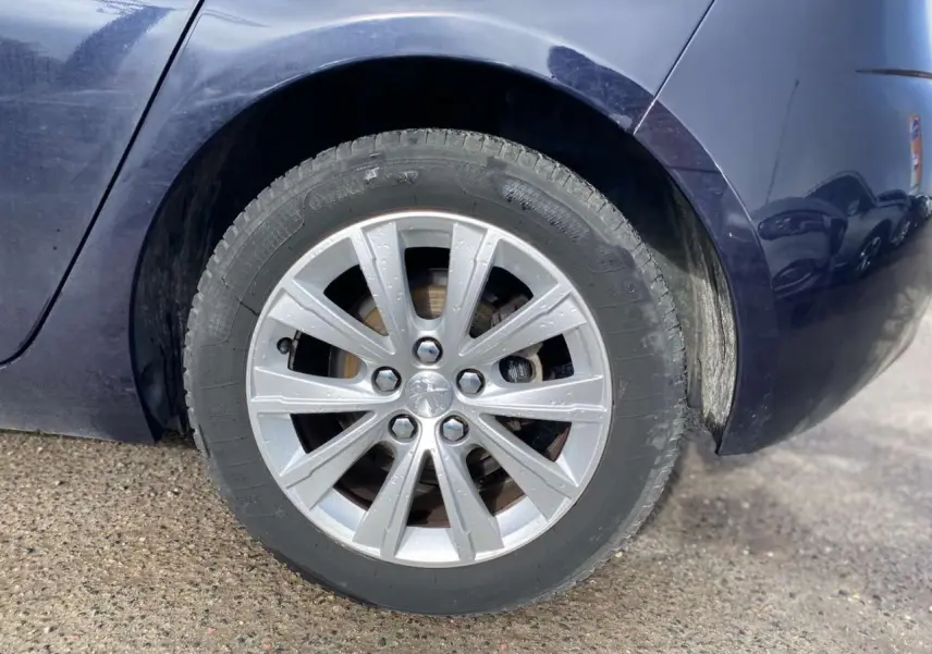 Gros plan sur la roue arrière droite d'une Peugeot 308 2018 bleu foncé avec jante argentée et pneus pluie.