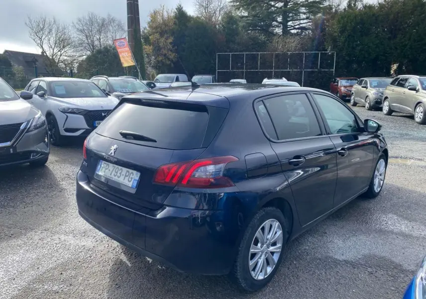 Peugeot 308 bleu foncé vue 3/4 arrière droit, avec feux arrière distinctifs et vitres teintées.
