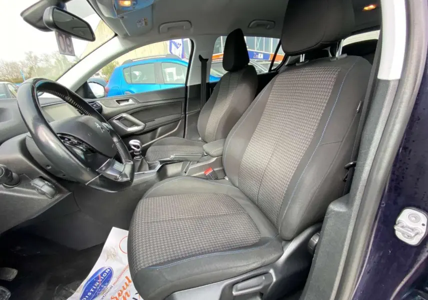 Vue intérieure côté conducteur de la Peugeot 308 2018 bleu foncé, montrant les sièges avant et le volant avec boîte manuelle.