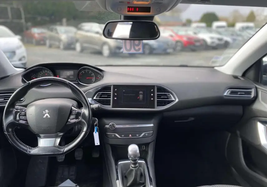 Vue intérieure avant du tableau de bord et volant noir d'une Peugeot 308 2018 avec boîte manuelle et écran central tactile.