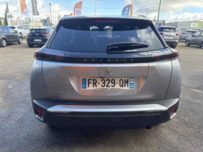 Vue arrière d’un Peugeot 2008 gris Artense avec feux arrière LED et lunette arrière teintée sur parking.