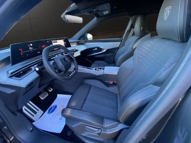 Vue intérieure côté conducteur du Peugeot 5008 Hybrid 145 GT 2025, sièges cuir gris noir avec logo brodé et tableau de bord numérique.