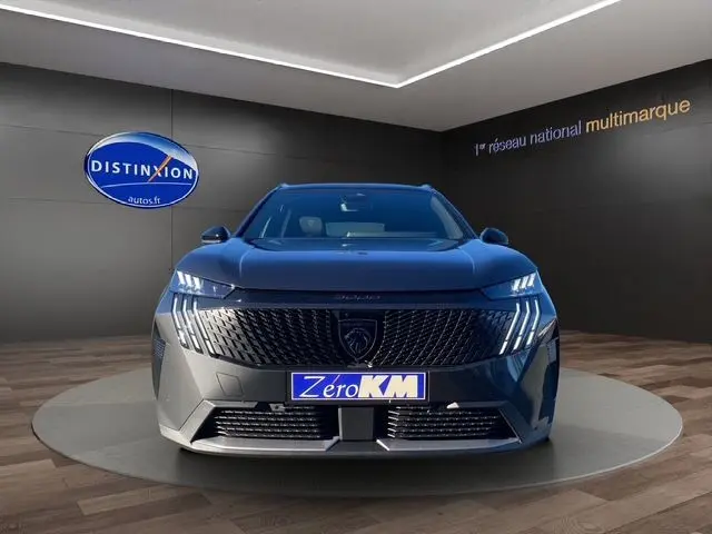 Vue frontale du Peugeot 5008 gris titane 2025 avec calandre distinctive et éclairage LED vertical en showroom.