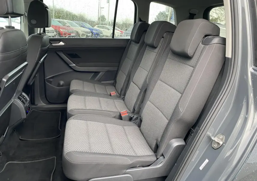Vue intérieure côté droit sur les sièges arrière gris tissu du Volkswagen Touran gris Dauphin 2025.