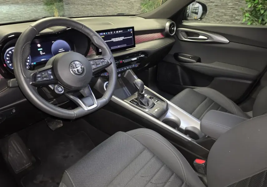 Vue intérieure côté conducteur de l'Alfa Romeo Tonale gris, avec volant sport cuir et tableau de bord digital.