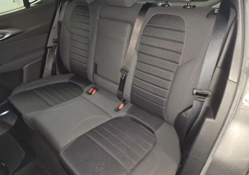 Vue intérieure de la banquette arrière noire de l'Alfa Romeo Tonale 1.3 PHEV avec ceinture de sécurité et accoudoir central.