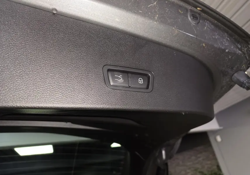 Gros plan sur le panneau noir intérieur du hayon ouvert de l'Alfa Romeo Tonale gris, avec boutons de fermeture et verrouillage.