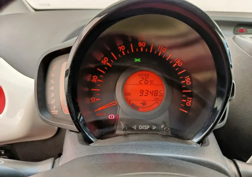 Vue rapprochée du tableau de bord de la Toyota Aygo blanc, affichant le compteur de vitesse et la température extérieure à 26°C.