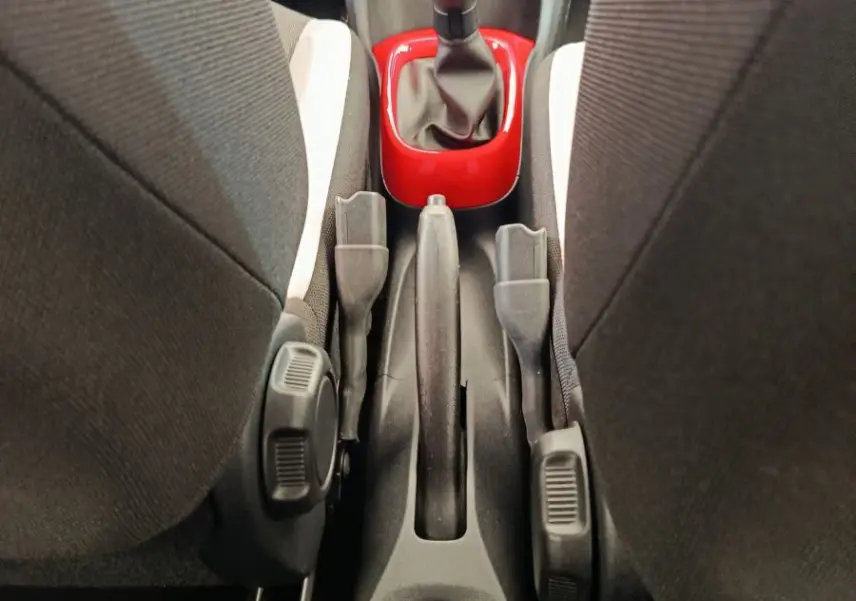 Vue intérieure centrée sur la console centrale d'une Toyota Aygo blanche, avec levier de vitesse manuel entouré d'un cadre rouge.