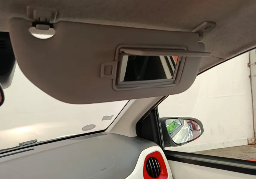 Intérieur de la Toyota Aygo blanc vue côté passager, avec pare-soleil baissé et miroir de courtoisie ouvert.