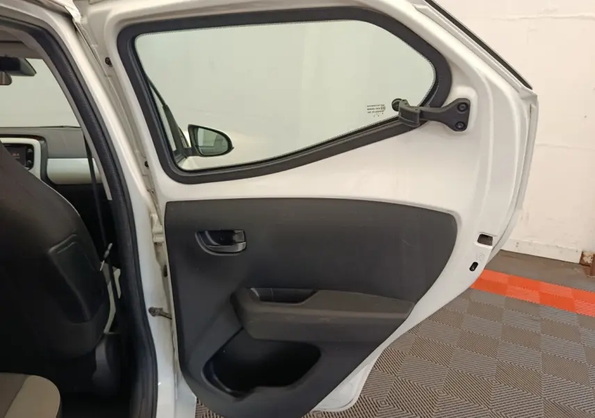 Vue intérieure de la porte arrière droite blanche d'une Toyota Aygo 2016 avec garniture noire et poignée intégrée.