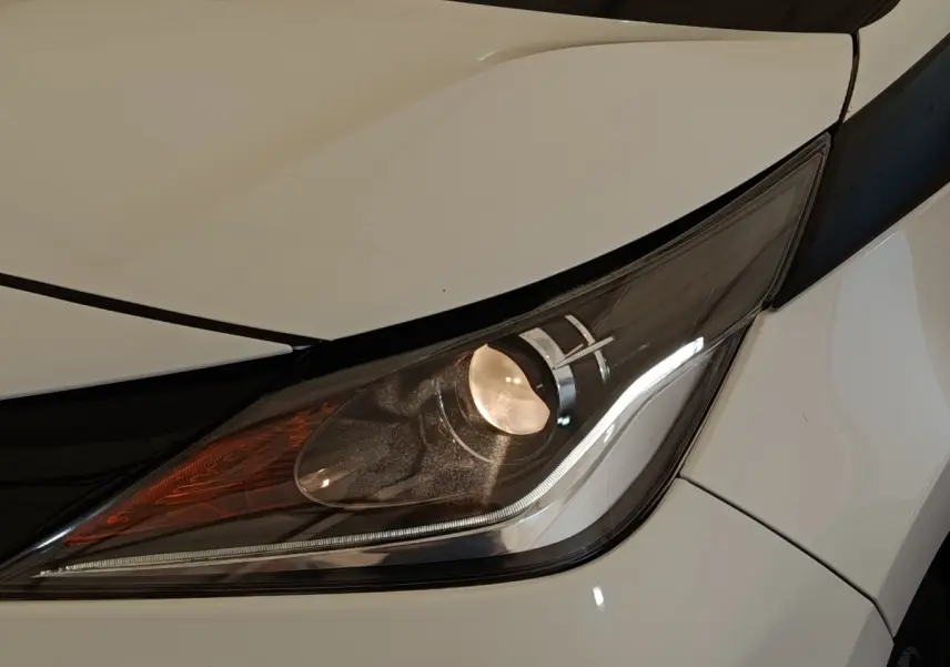 Gros plan sur le phare avant droit d’une Toyota Aygo blanche, mettant en valeur ses feux LED et détails du capot.