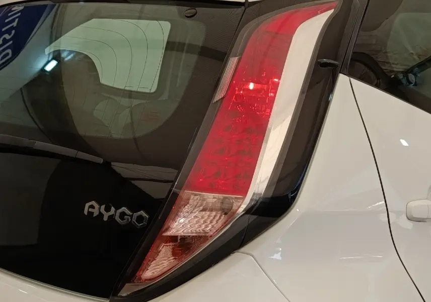 Gros plan sur l’arrière droit blanc d’une Toyota Aygo 2016, mettant en valeur le feu arrière et le logo AYGO.