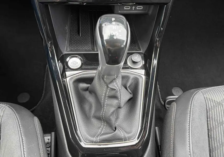 Gros plan sur la console centrale du Volkswagen T-Cross gris, mettant en valeur le levier de vitesse manuel et le bouton start/stop.