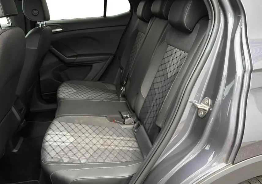 Vue intérieure côté droit sur les sièges arrière gris à motifs du Volkswagen T-Cross 2025 avec porte ouverte.