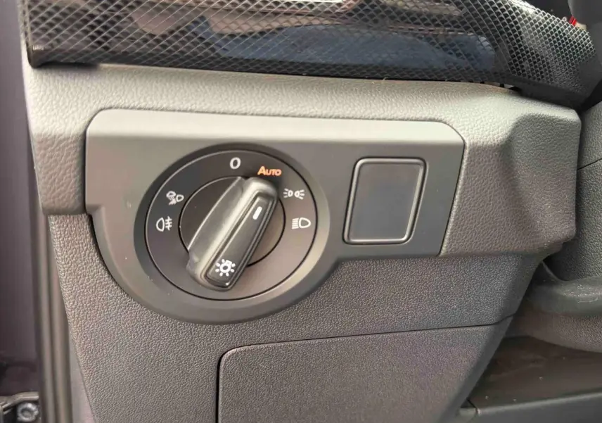 Gros plan sur le bouton de commande des phares avec réglage automatique dans l’habitacle du Volkswagen T-Cross gris.
