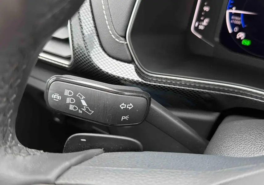 Gros plan sur la manette de clignotant noire à gauche du volant dans l’habitacle du Volkswagen T-Cross gris 2025.