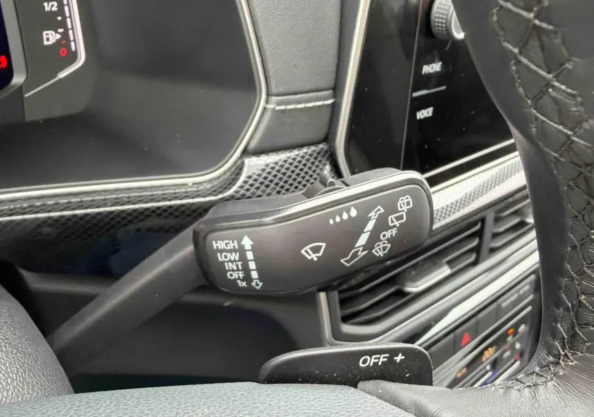 Gros plan sur la commande d’essuie-glace à gauche du volant du Volkswagen T-Cross gris, intérieur noir.