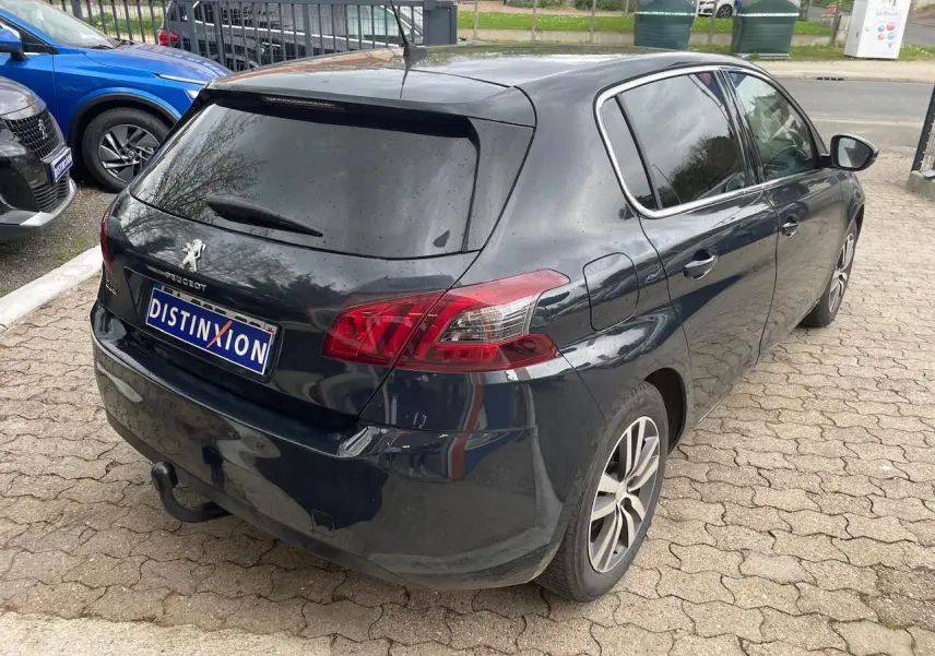 Vue 3/4 arrière droite d'une Peugeot 308 gris hurricane avec vitres arrière surteintées et feux arrière rouges.