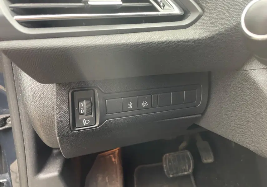 Détail intérieur montrant les commandes d'éclairage et d'assistance au conducteur sur une Peugeot 308 gris Hurricane de 2018.