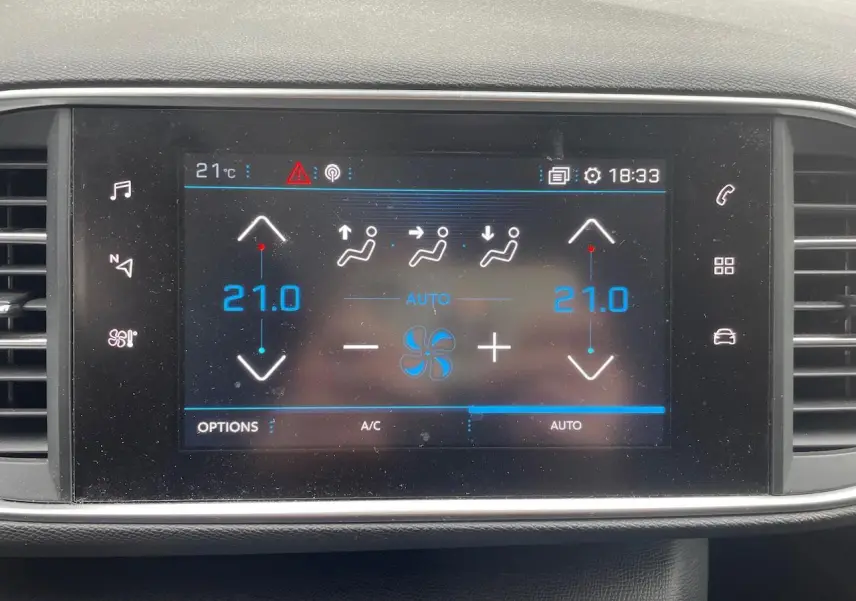 Écran tactile central de la Peugeot 308 gris Hurricane montrant la climatisation réglée à 21°C en mode automatique