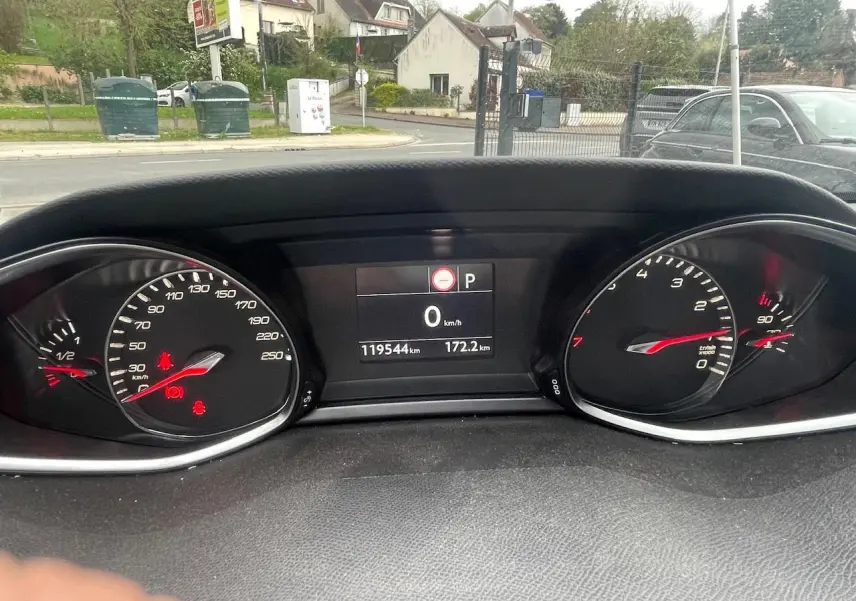 Vue rapprochée du tableau de bord de la Peugeot 308 gris hurricane, affichant le compteur et l'écran digital au repos.