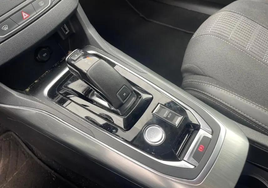 Gros plan sur la console centrale de la Peugeot 308 gris hurricane, avec levier de boîte auto et bouton start/stop.