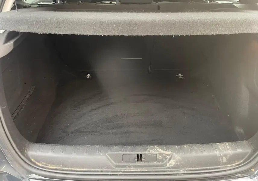 Coffre ouvert vu de l'arrière d'une Peugeot 308 gris hurricane, montrant un espace de chargement vide et propre.