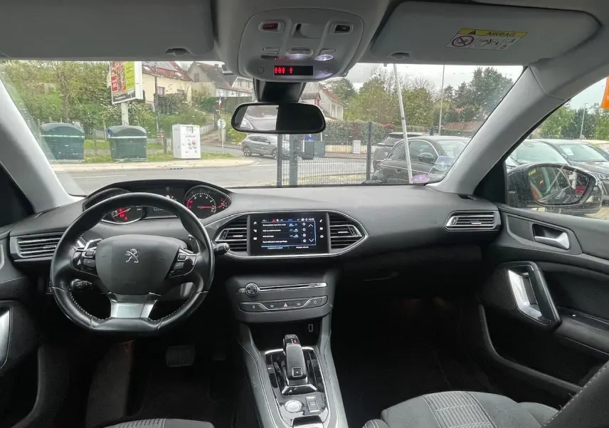 Vue intérieure avant de la Peugeot 308 gris Hurricane de 2018, montrant le tableau de bord, le volant multifonction et l'écran tactile central.