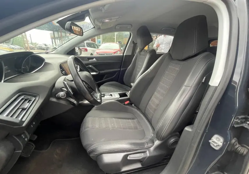 Intérieur avant droit de la Peugeot 308 gris hurricane, sièges noirs avec surpiqûres blanches et tableau de bord moderne.