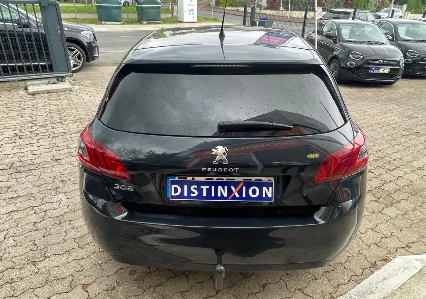 Vue arrière d'une Peugeot 308 gris foncé avec vitres surteintées et logo distinctif sur le hayon.