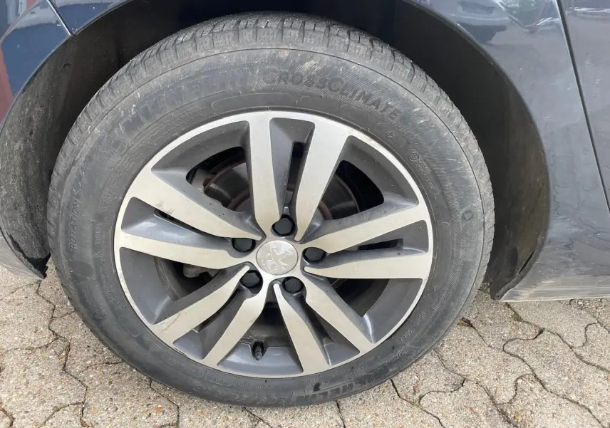 Gros plan sur la roue avant gauche d'une Peugeot 308 gris Hurricane avec jante alliage à huit branches.