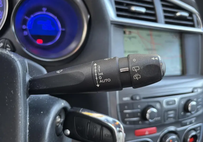 Gros plan sur la commande d'essuie-glace gauche du tableau de bord d'une Citroën C4 gris clair avec écran de navigation en arrière-plan.