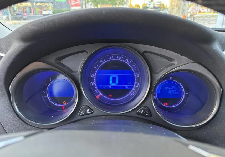 Tableau de bord numérique bleu de la Citroën C4 2012, affichant la vitesse et compte-tours au centre du volant.