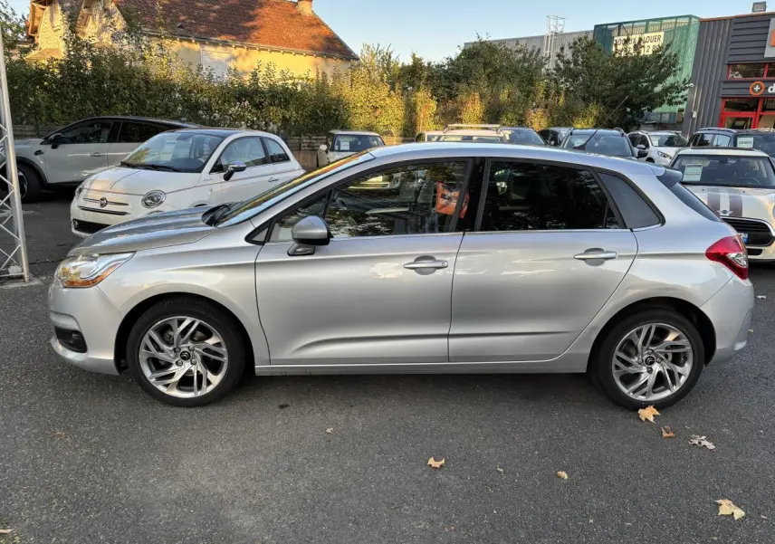 Profil côté gauche d'une Citroën C4 gris clair de 2012, avec vitres arrière surteintées et jantes alliage visibles.