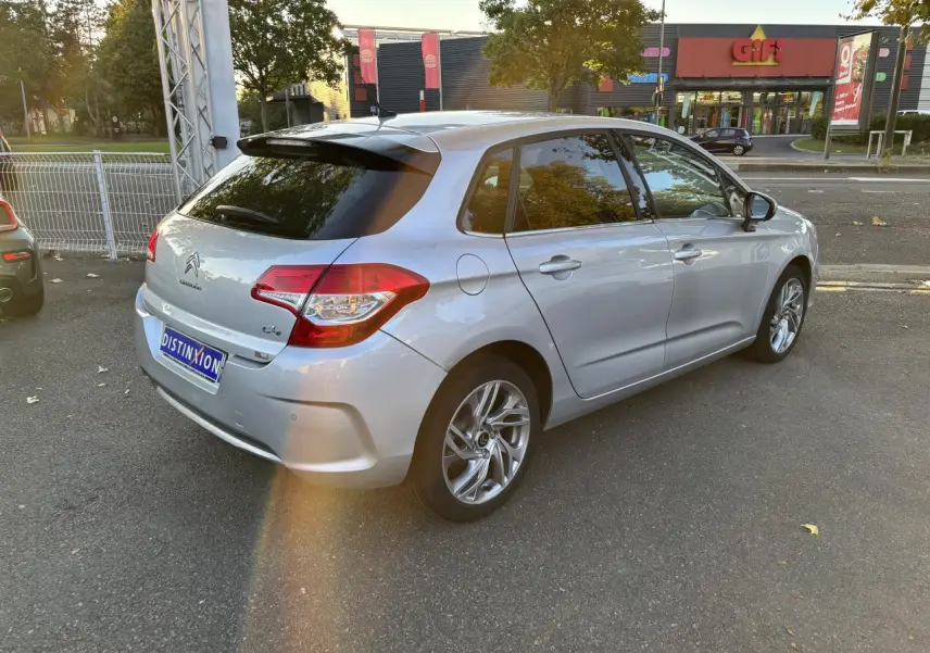 Vue 3/4 arrière droite d'une Citroën C4 gris clair avec vitres arrière surteintées et jantes alliage.